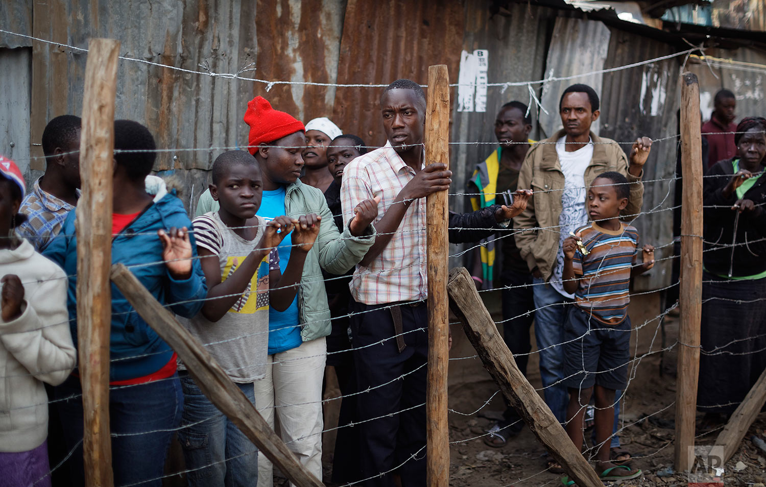  Residents look through a fence at the scene near the body of a man who had been shot in the head and who the crowd claimed had been shot by police, in the Mathare area of Nairobi, Kenya, Wednesday, Aug. 9, 2017. Kenya's election took an ominous turn on Wednesday as violent protests erupted in the capital. (AP Photo/Ben Curtis) 