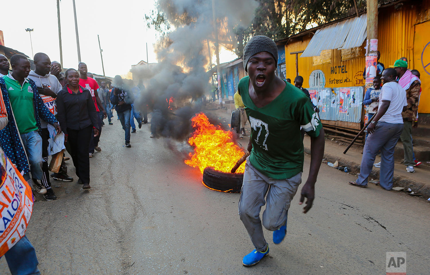  A man pulls a burning tire in Kibera, Nairobi, Kenya, as others block roads with stones to protest in support of Kenyan opposition leader and presidential candidate Raila Odinga, Wednesday, Aug. 9, 2017. Kenya's election took an ominous turn on Wednesday as violent protests erupted in the capital and elsewhere after opposition leader Raila Odinga alleged fraud, saying hackers used the identity of a murdered official to infiltrate the database of the country's election commission and manipulate results. (AP Photo/Brian Inganga) 