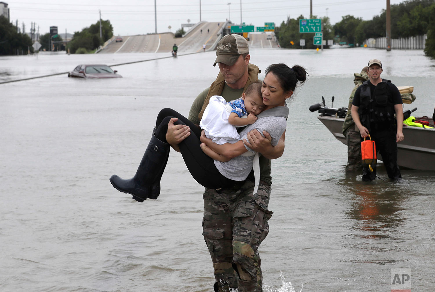 Houston Police SWAT officer Daryl Hudeck carries Connie Pham and her 13-month-old son Aiden after rescuing them from their home surrounded by floodwaters from Tropical Storm Harvey Sunday, Aug. 27, 2017, in Houston. (AP Photo/David J. Phillip)