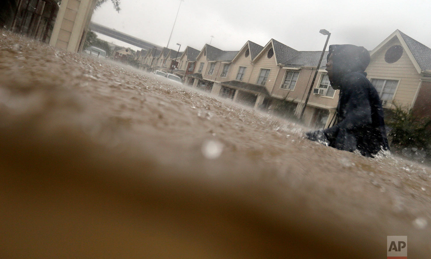 A child makes his way through floodwaters from Tropical Storm Harvey while checking on neighbors at his apartment complex in Houston, Sunday, Aug. 27, 2017. (AP Photo/LM Otero)