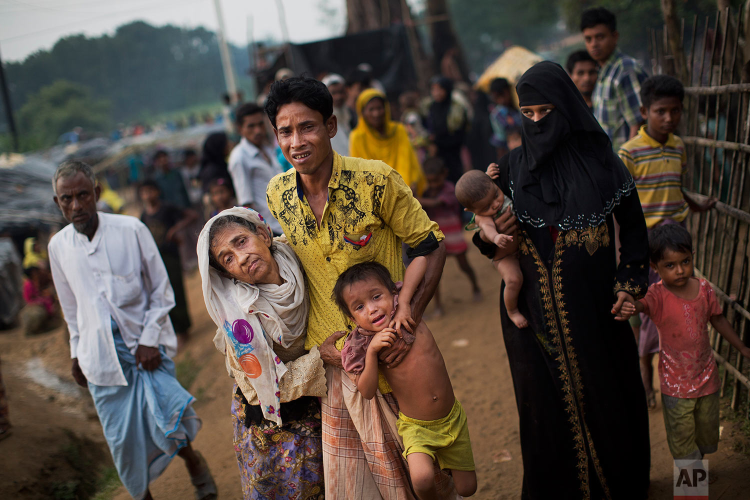 An exhausted Rohingya helps an elderly family member and a child as they arrive at Kutupalong refugee camp after crossing from Myanmmar to the Bangladesh side of the border, in Ukhia, Tuesday, Sept. 5, 2017. The man said he lost several family members in Myanmar. Tens of thousands of Rohingya Muslims, fleeing the latest round of violence to engulf their homes in Myanmar, have been walking for days or handing over their meager savings to Burmese and Bangladeshi smugglers to escape what they describe as certain death. (AP Photo/Bernat Armangue)