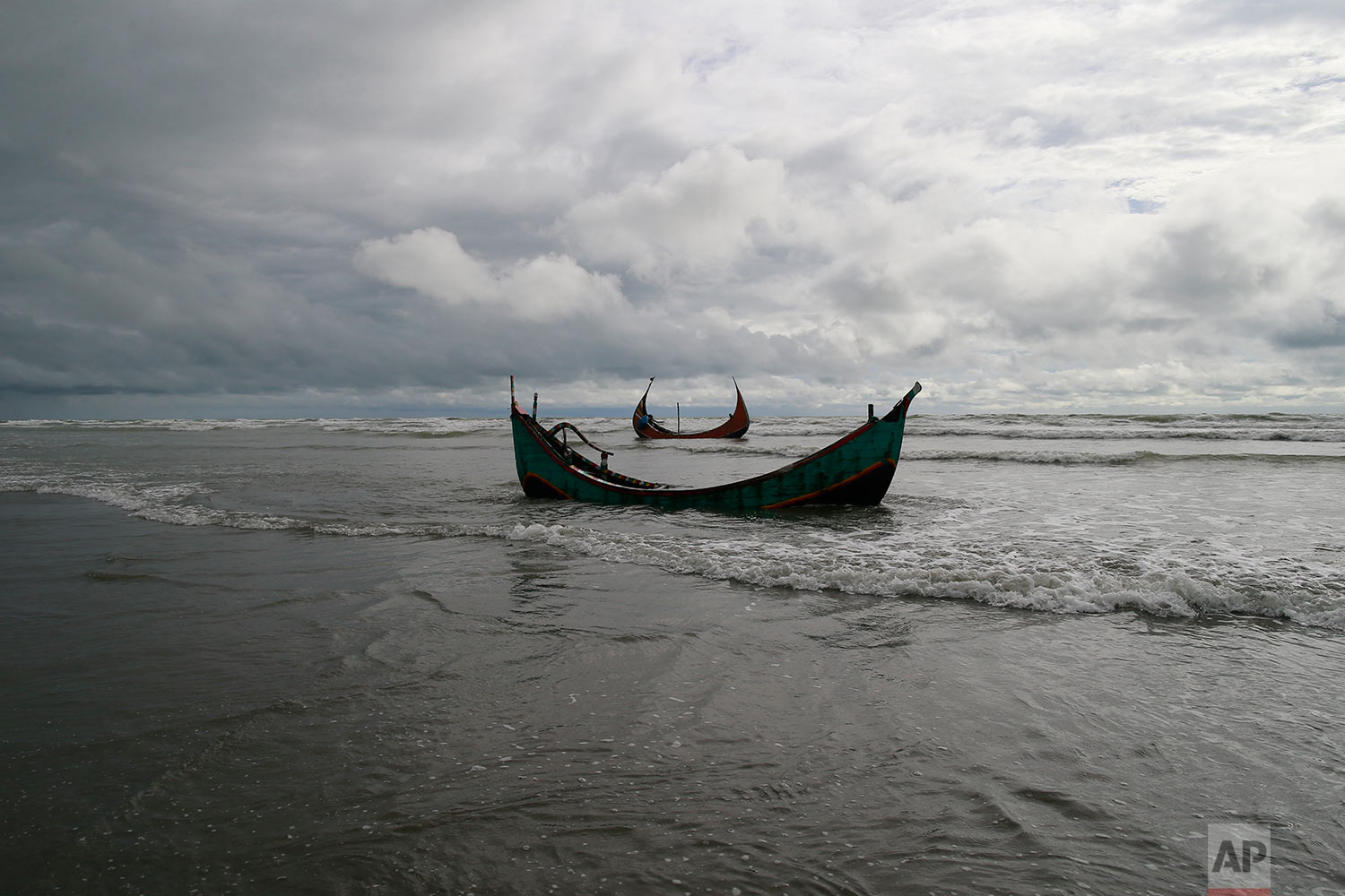 Two among three boats that capsized while being used by fleeing Rohingya is seen on the Bay of Bengal coast, after being recovered by Bangladeshi villagers at Shah Porir Deep, in Teknak, Bangladesh, Thursday, Aug.31, 2017. Three boats carrying ethnic Rohingya fleeing violence in Myanmar have capsized in Bangladesh and 26 bodies of women and children have been recovered, officials said Thursday. Last week, a group of ethnic minority Rohingya insurgents attacked at least two dozen police posts in Myanmar's Rakhine state, triggering fighting with security forces that left more than 100 people dead and forced at least 18,000 Rohingya to flee into neighboring Bangladesh. (AP Photo/Suvra Kanti Das)