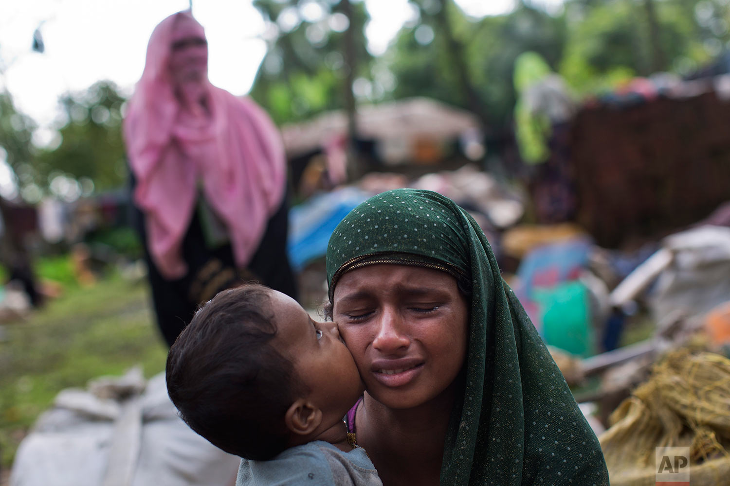 A Rohingya Muslim child places a kiss on his mother's cheek as they rest after having crossed over from Myanmar to the Bangladesh side of the border near Cox's Bazar's Teknaf area, Saturday, Sept. 2, 2017. (AP Photo/Bernat Armangue)