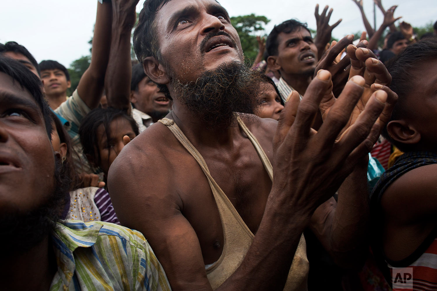 A Rohingya man stretches his arms out for food distributed by local volunteers, with bags of puffed rice stuffed into his vest at Kutupalong, Bangladesh, Saturday, Sept. 9, 2017. (AP Photo/Bernat Armangue)