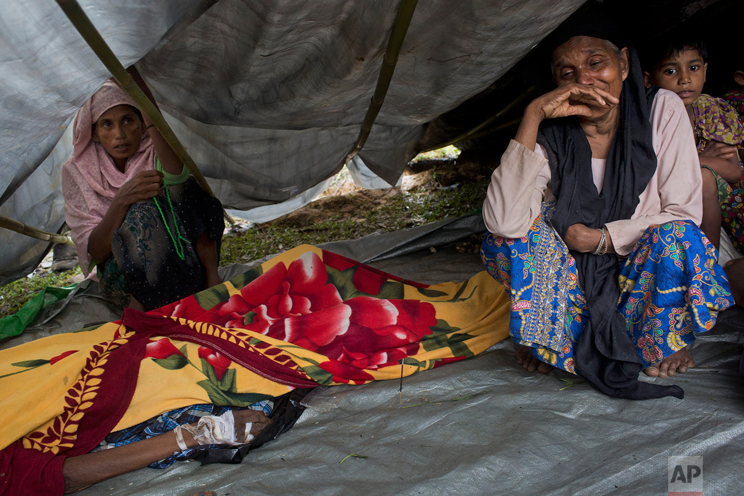 Newly arrived Rohingyas mourn by the body of a family member Ali Akbar, 70, in a makeshift tent in Kutupalong, Bangladesh, Friday, Sept. 8, 2017. According to family members, Akbar was shot in the hand and beaten with rifle butts by Myanmar soldiers before the family escaped to Bangladesh. He died today. (AP Photo/Bernat Armangue)