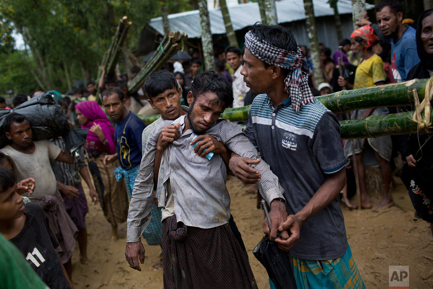 Kifawet Ullah is helped by other newly arrived Rohingya after he collapsed while waiting to have his token validated in order to collect a bag of rice distributed by aid agencies in Kutupalong, Bangladesh, Saturday, Sept. 9, 2017. (AP Photo/Bernat Armangue)
