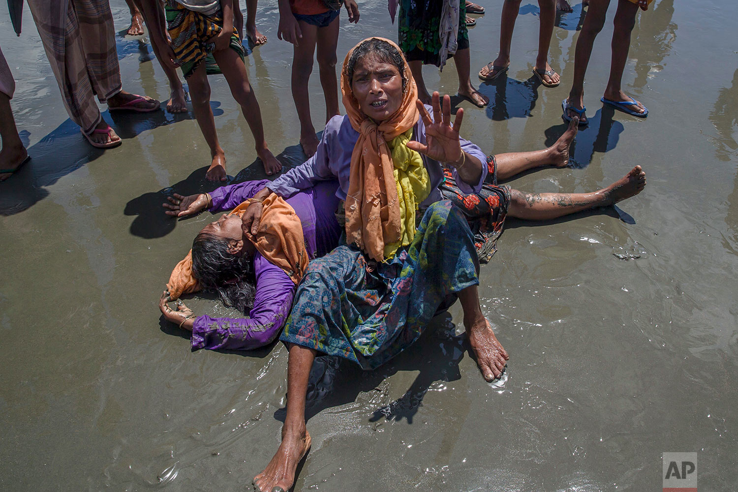 A Rohingya Muslim woman, who crossed over from Myanmar into Bangladesh, shouts for help as a relative lies unconscious after the boat they were traveling in capsized minutes before reaching shore at Shah Porir Dwip, Bangladesh, Thursday, Sept. 14, 2017.  (AP Photo/Dar Yasin)