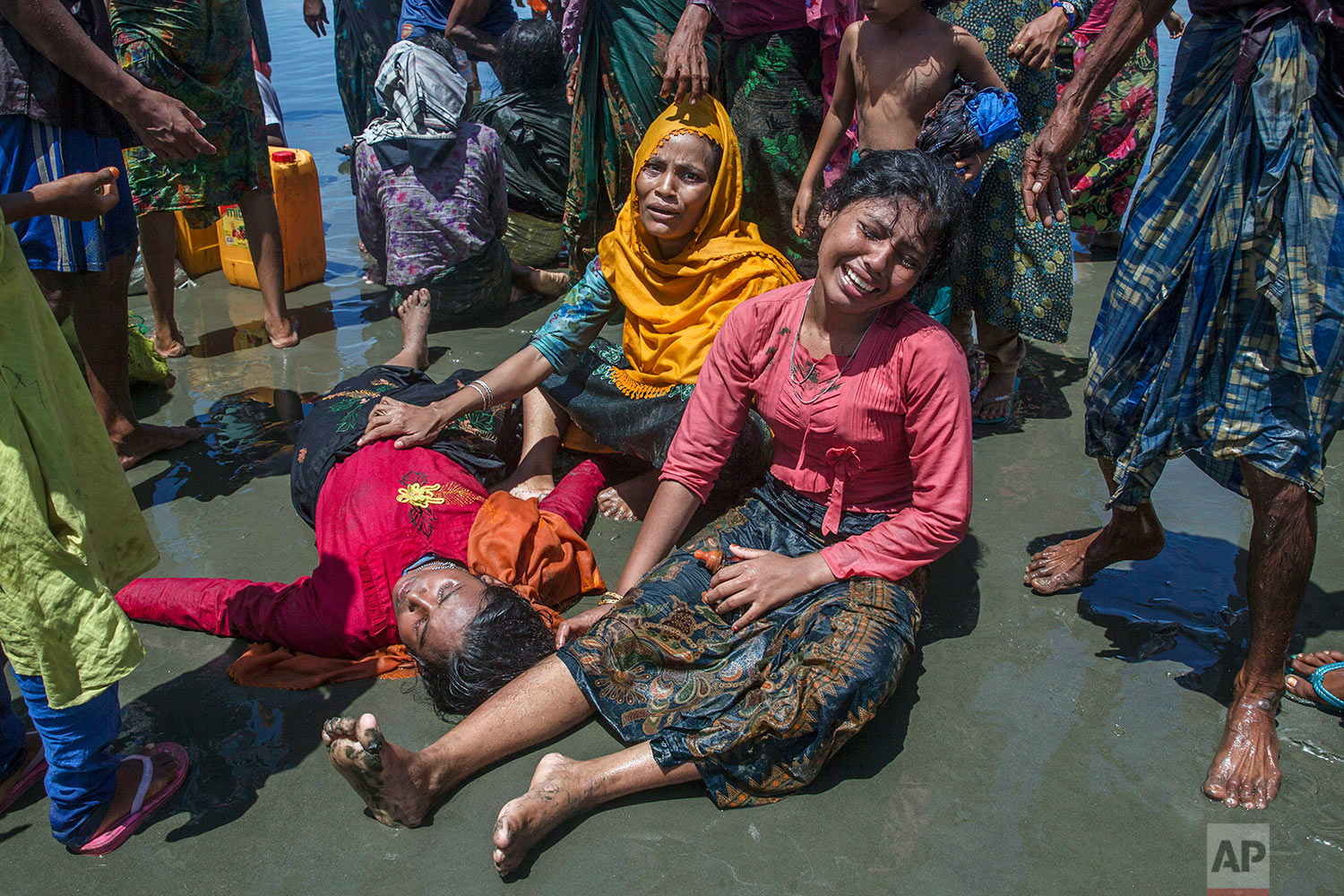 Rohingya Muslim women, who crossed over from Myanmar into Bangladesh, wail as a relative lies unconscious after the boat they were traveling in capsized minutes before reaching shore at Shah Porir Dwip, Bangladesh, Thursday, Sept. 14, 2017. The woman survived. (AP Photo/Dar Yasin)