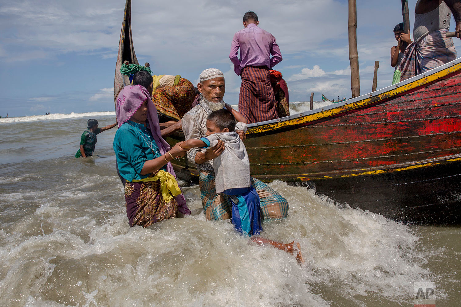 An elderly Rohingya Muslim man helps a boy get off a boat after they arrived from Myanmar to Bangladesh in Shah Porir Dwip, Bangladesh, Thursday, Sept. 14, 2017. (AP Photo/Dar Yasin)