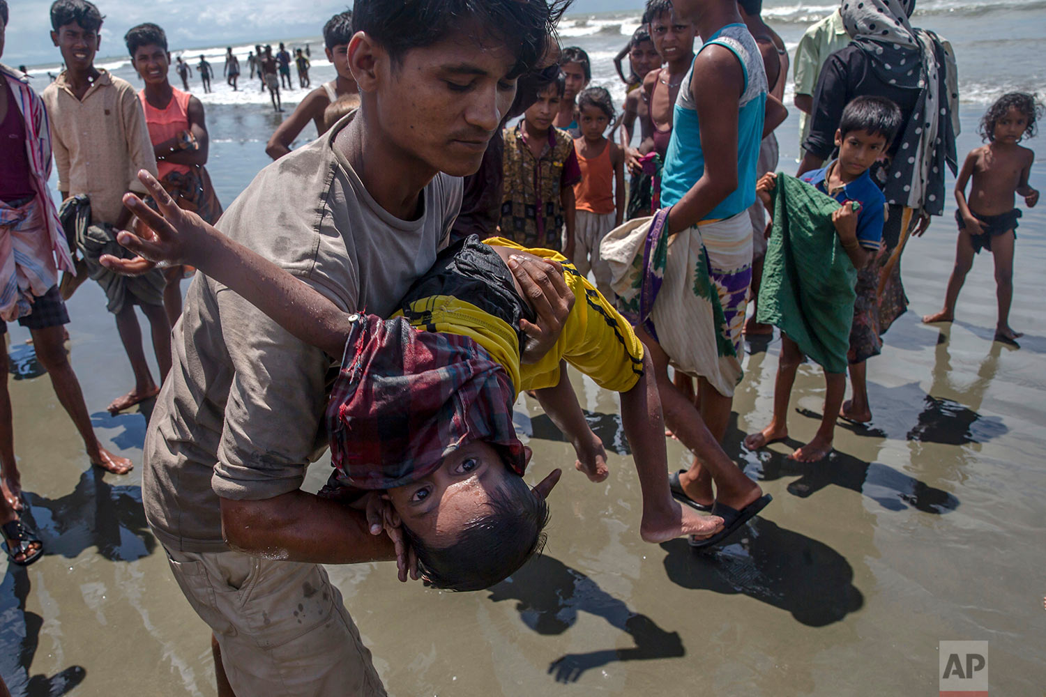 A man shakes a Rohingya Muslim boy while trying to revive him after the boat he was traveling in capsized just before reaching shore at Shah Porir Dwip, Bangladesh, Thursday, Sept. 14, 2017. (AP Photo/Dar Yasin)
