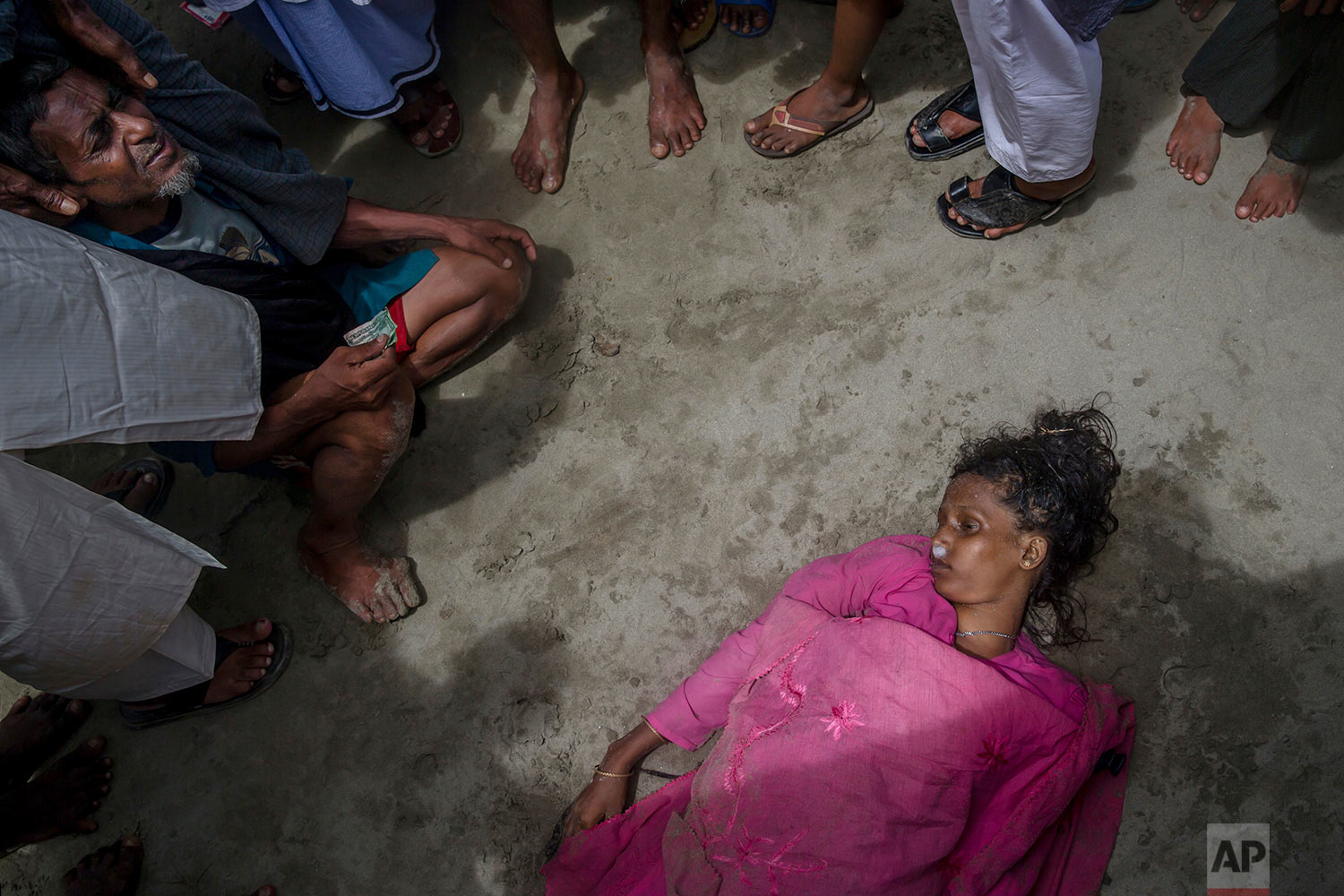 A Rohingya Muslim man Mohammad Islam sits beside the body of his daughter-in-law Anwara Begum who died when the boat they were traveling in capsized minutes before reaching shore in Shah Porir Dwip, Bangladesh, Thursday, Sept. 14, 2017. (AP Photo/Dar Yasin)