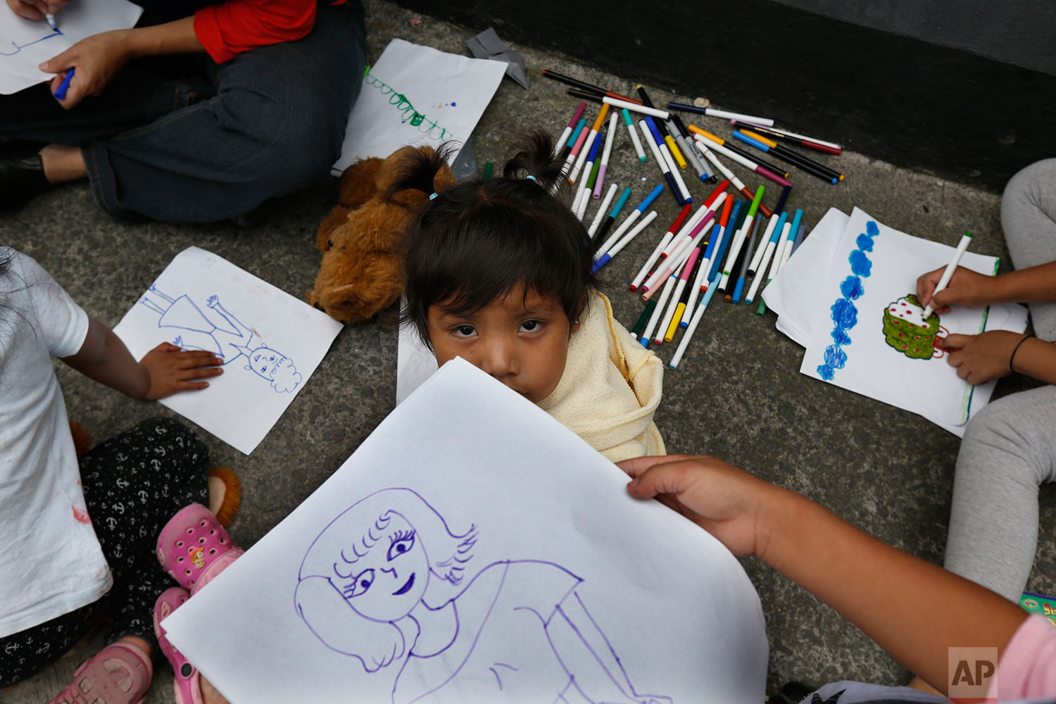 Children from an Otomi indigenous family pass the time drawing, on the sidewalk of their apartment building after it was declared uninhabitable by authorities after Tuesday's 7.1 earthquake, at the corner of Guanajuato and Monterrey streets in the Roma neighborhood of Mexico City, Saturday, Sept. 23, 2017. (AP Photo/Marco Ugarte)