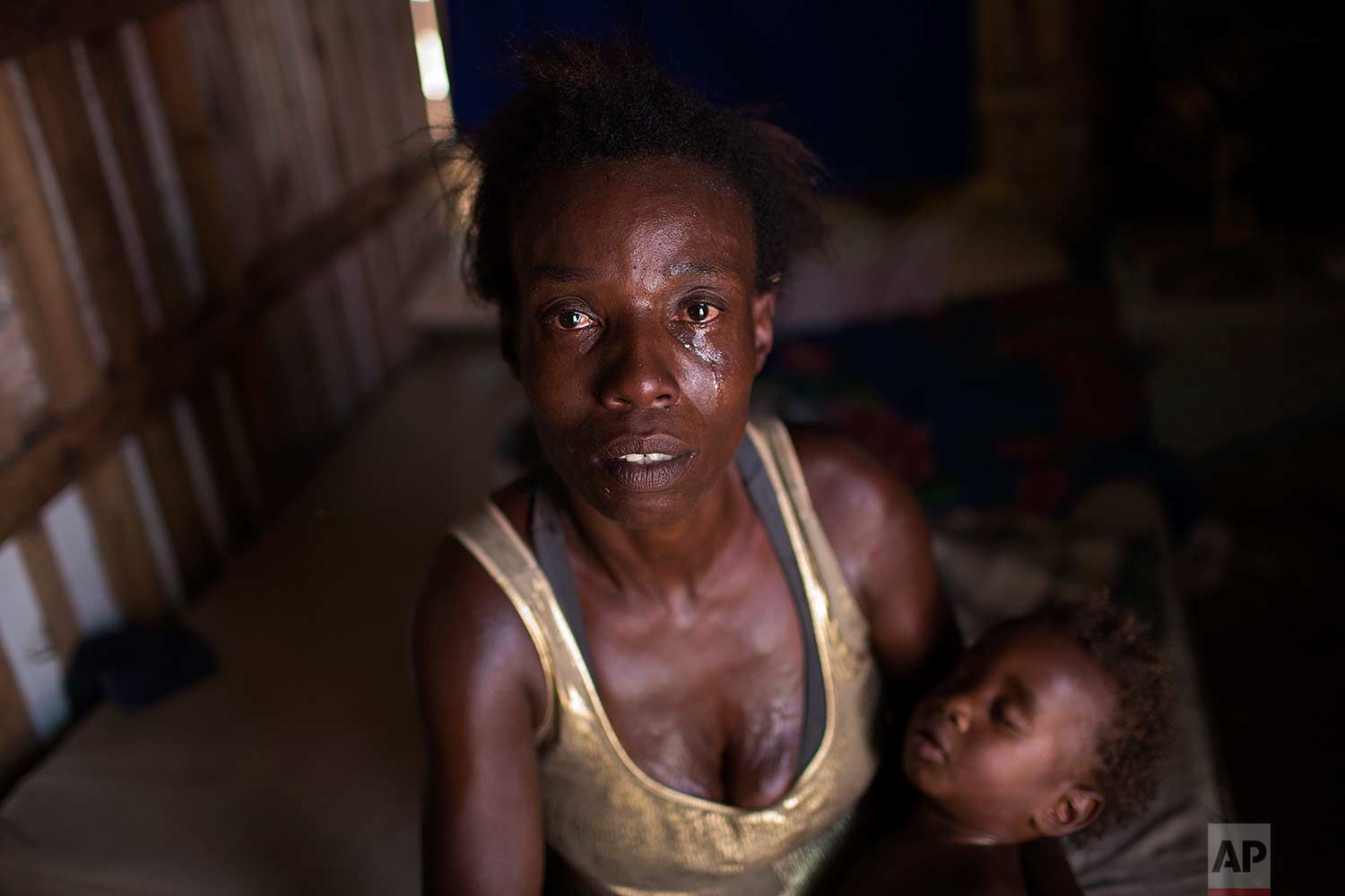  In this Oct. 20, 2017 photo, Simone Batista, holding her baby Arthur, looks into the camera as tears roll down her cheeks while she recounts being cut from the "Bolsa Familia" government subsidy program for low-income people, at her shack home in the Jardim Gramacho slum of Rio de Janeiro, Brazil. (AP Photo/Silvia Izquierdo) 