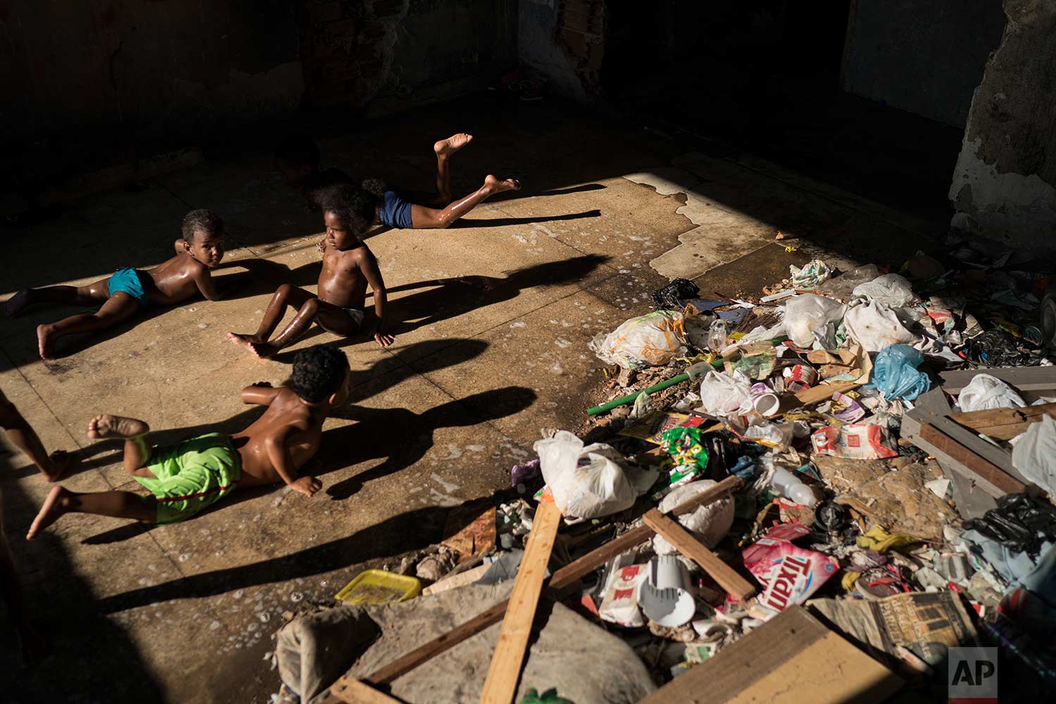  In this Sept. 10, 2017 photo, children slide on a puddle near trash as they play in a squatter building that used to house the Brazilian Institute of Geography and Statistics (IBGE) in the Mangueira slum of Rio de Janeiro, Brazil. (AP Photo/Felipe Dana) 