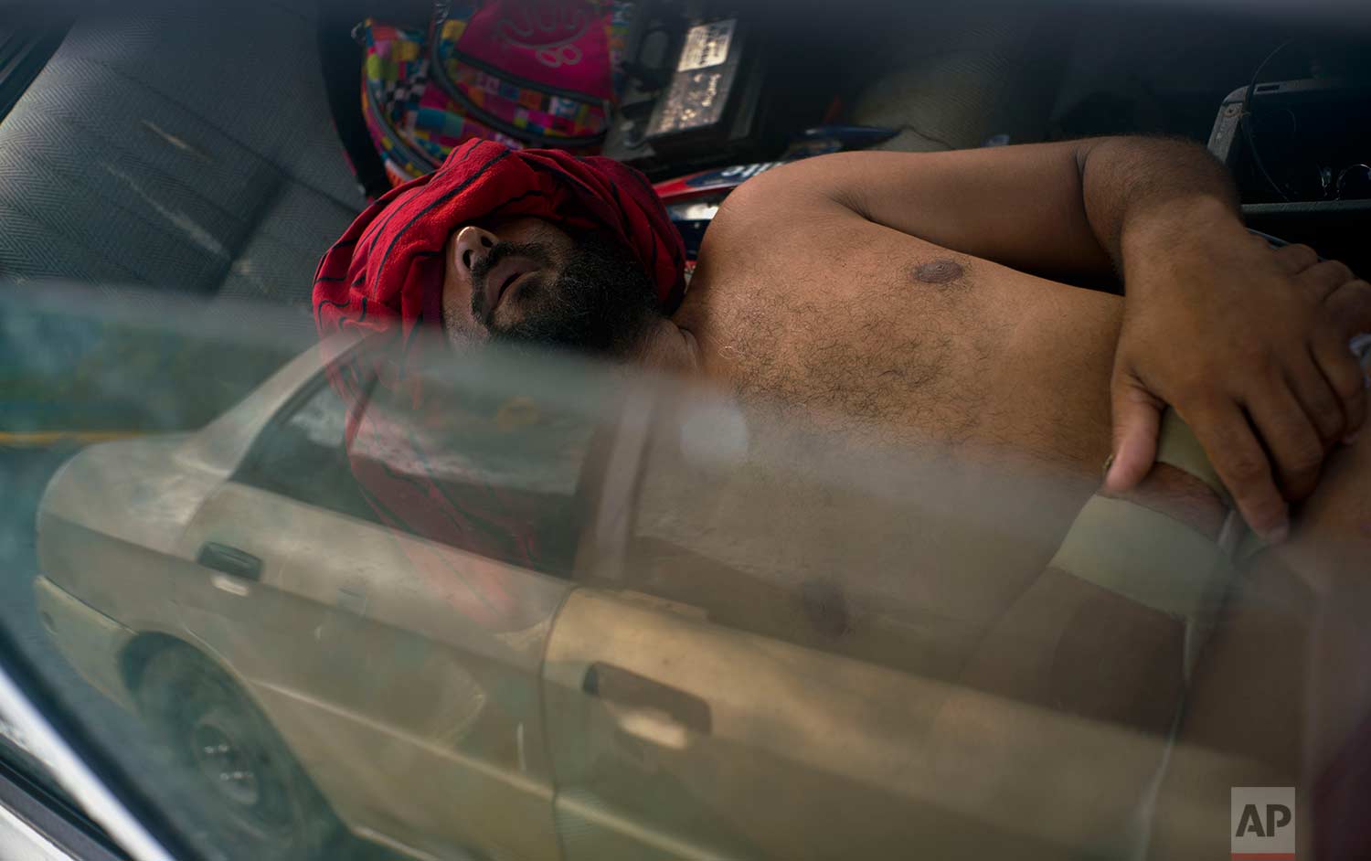  In this Saturday, Oct. 14, 2017 photo, Arturo de Jesus Melendez sleeps in his car with a shirt over his eyes, after he couldn't sleep in the school-turned-shelter due to the noise in Toa Baja, Puerto Rico. (AP Photo/Ramon Espinosa) 
