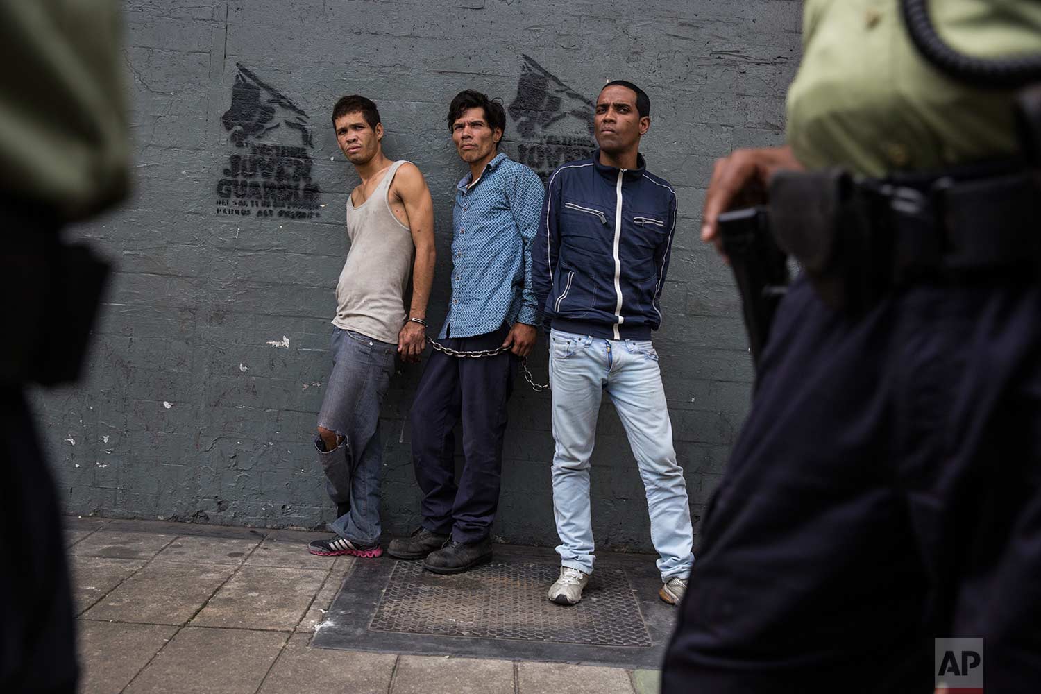  Suspected thieves chained together look at police after they were detained in downtown in Caracas, Venezuela, Wednesday, Oct. 25, 2017. (AP Photo/Rodrigo Abd) 