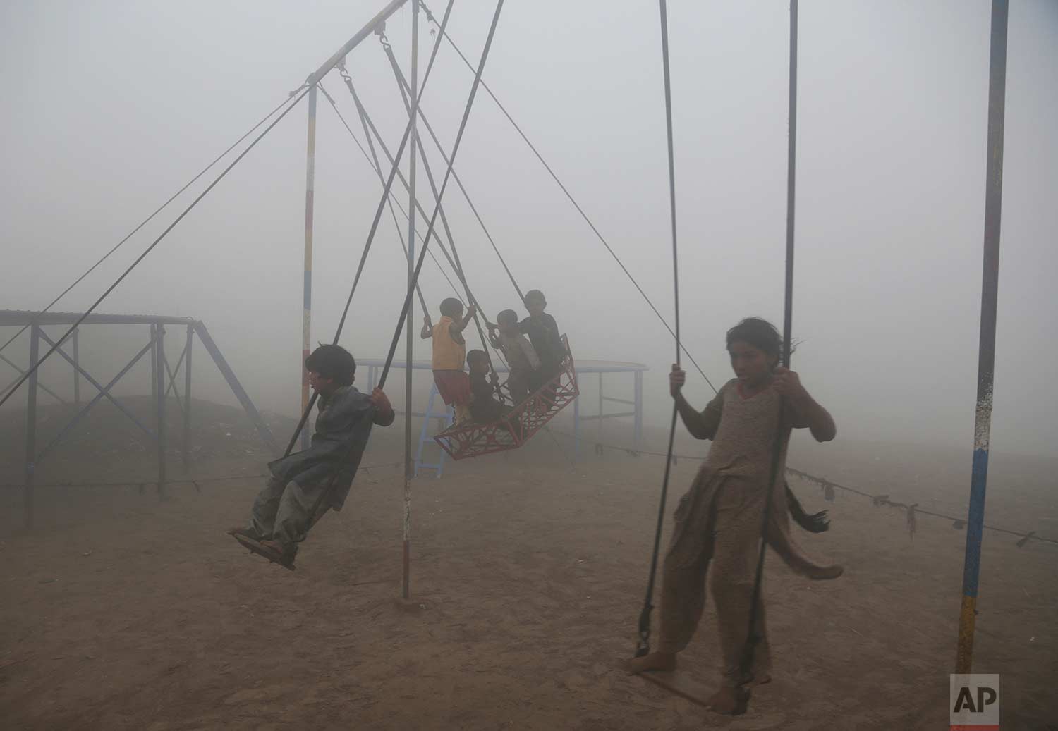  Children ride swings in a playground engulfed by smog in Lahore, Pakistan, Saturday, Nov. 11, 2017. Officials said smog has enveloped much of the country, causing highway accidents and respiratory problems, and forcing many residents to stay home. (AP Photo/K.M. Chaudary) 