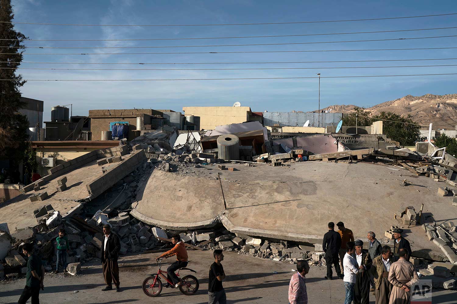  People walk next to a destroyed building after an earthquake in the city of Darbandikhan, northern Iraq, Monday, Nov. 13, 2017. (AP Photo/Felipe Dana) 