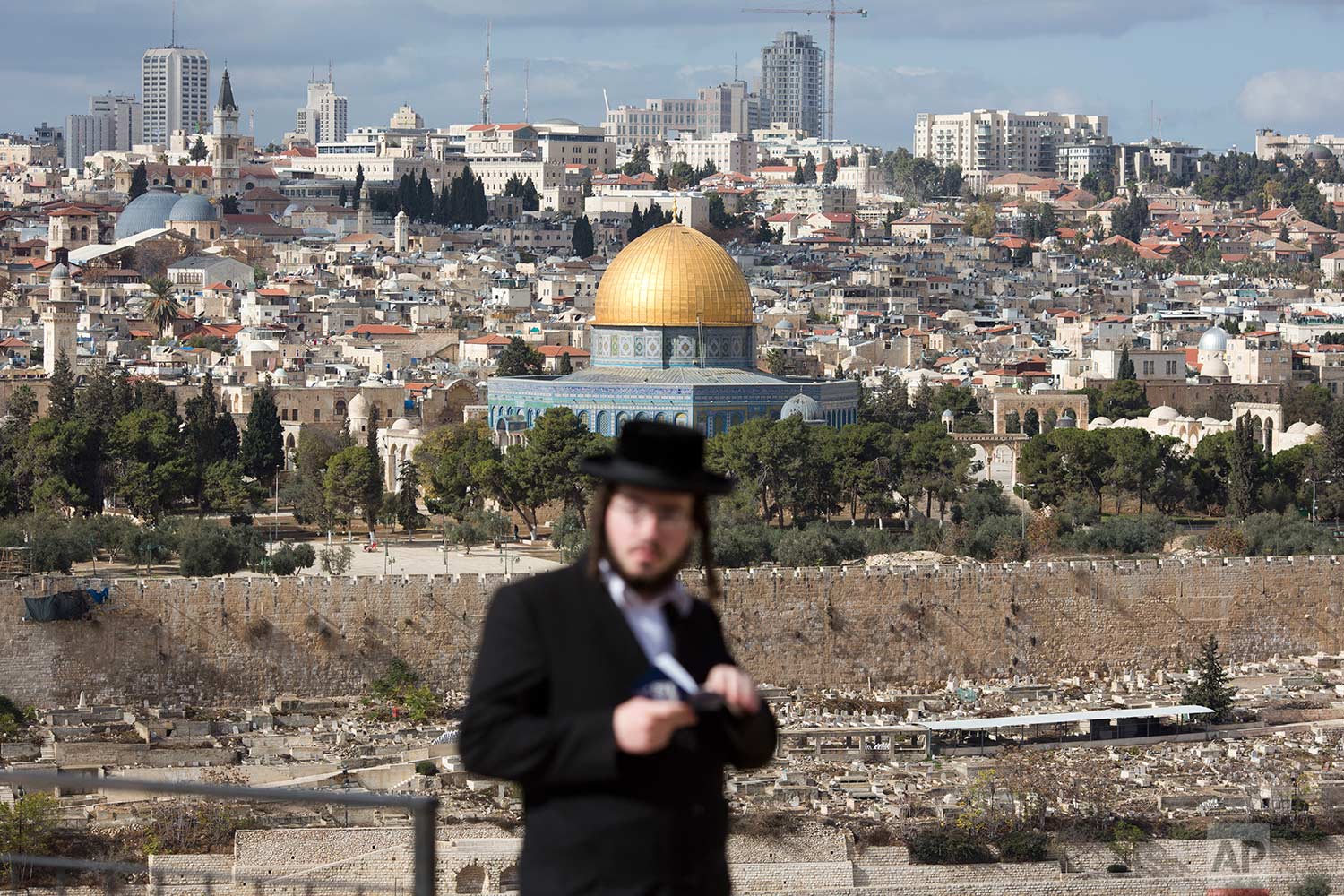  An orthodox Jewish man reads from a holy book in a cemetery near the Dome of the Rock Mosque in the Al Aqsa Mosque compound in Jerusalem's Old City, Thursday, Dec. 7, 2017. A day earlier, U.S. President Donald Trump announced his decision to recognize Jerusalem as Israel's capital. (AP Photo/Ariel Schalit) 