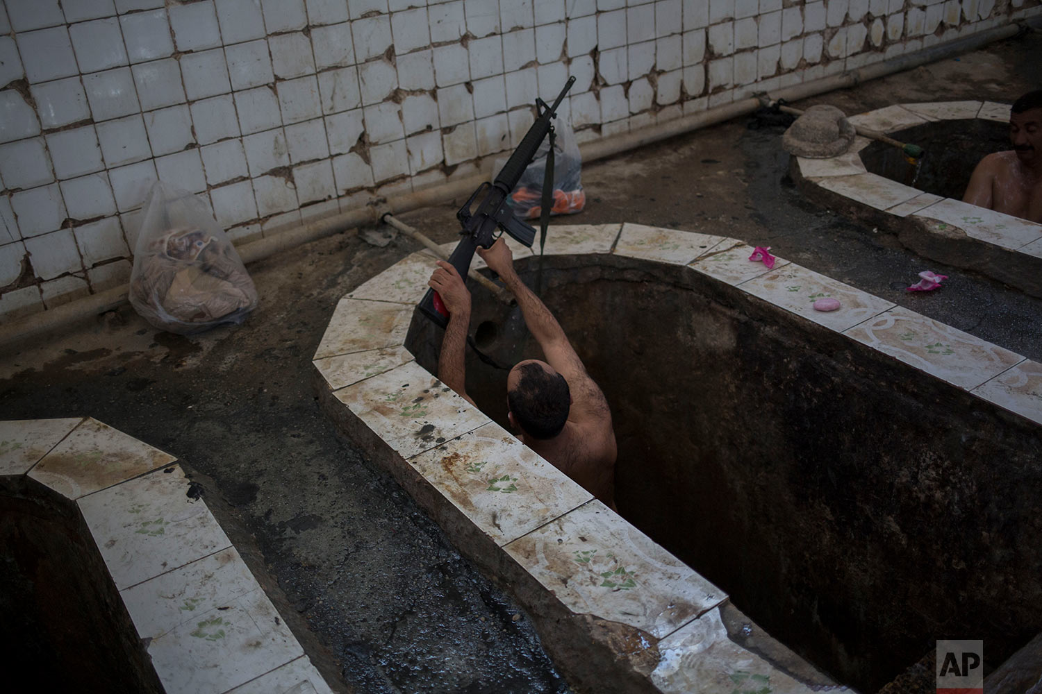  A federal police officer puts his machine gun on the edge of the bath in the Hamam Alil spa, south of Mosul, Iraq, Thursday April, 27, 2017. The spa reopened several months ago after the town was liberate from the Islamic State group. Many Iraqi soldiers visit the spa, located half an hour south of Mosul, in between fighting against the Islamic State group for relaxation. (AP Photo/Bram Janssen) 