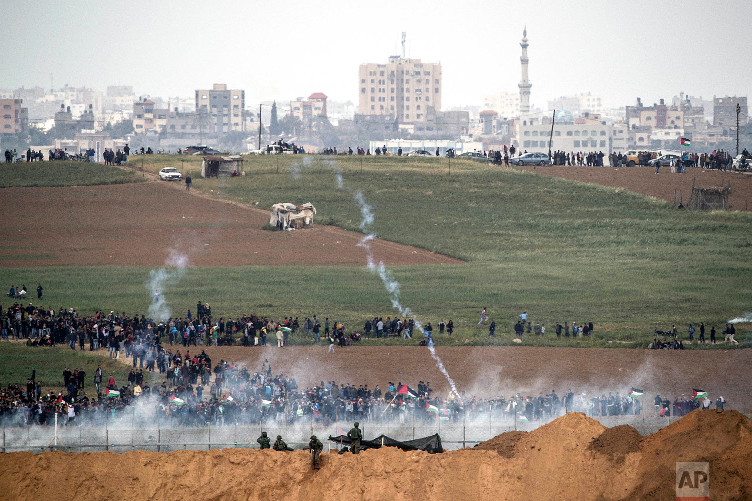  Israeli soldiers shoot tear gas toward Palestinian protesters as they gather on the Israel Gaza border, Friday, March 30, 2018. (AP Photo/Tsafrir Abayov) 