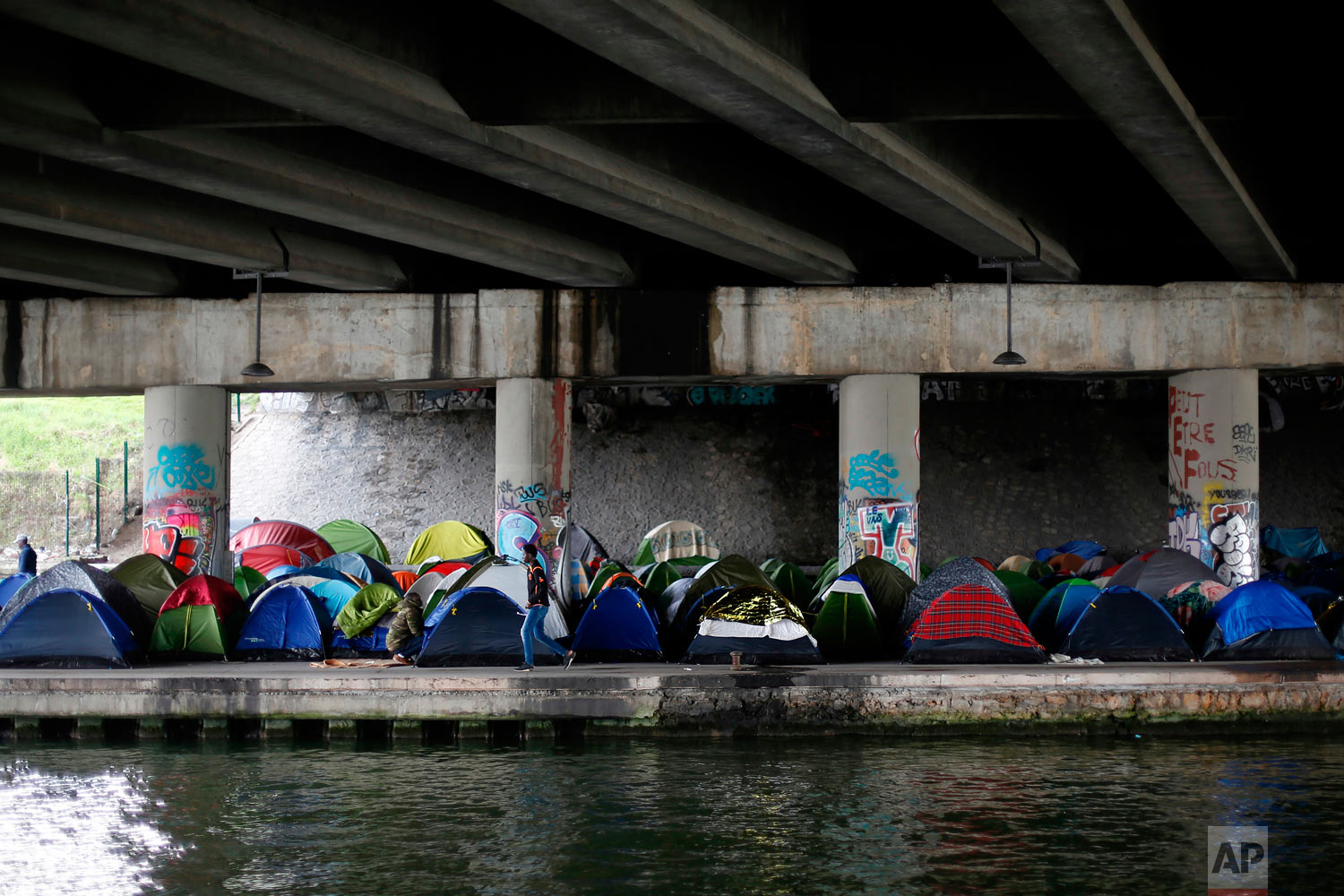  A migrant walks by tents in a makeshift camp along the Canal Saint Denis, in Paris, Wednesday, April 4, 2018. (AP Photo/Thibault Camus) 