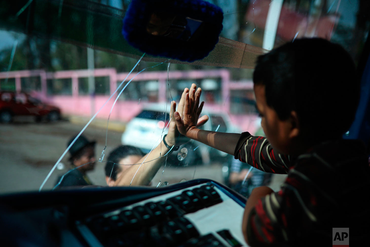  A boy says goodbye to a friend through the windshield of a bus that will carry him to Mexico City from the sports club where Central American migrants traveling with the annual "Stations of the Cross" caravan had been camping out in Matias Romero, Oaxaca State, Mexico, Thursday, April 5, 2018. Migrants in the caravan that drew criticism from U.S. President Donald Trump began packing up their meager possessions and boarding buses to the Mexican capital and the nearby city of Puebla. (AP Photo/Felix Marquez) 