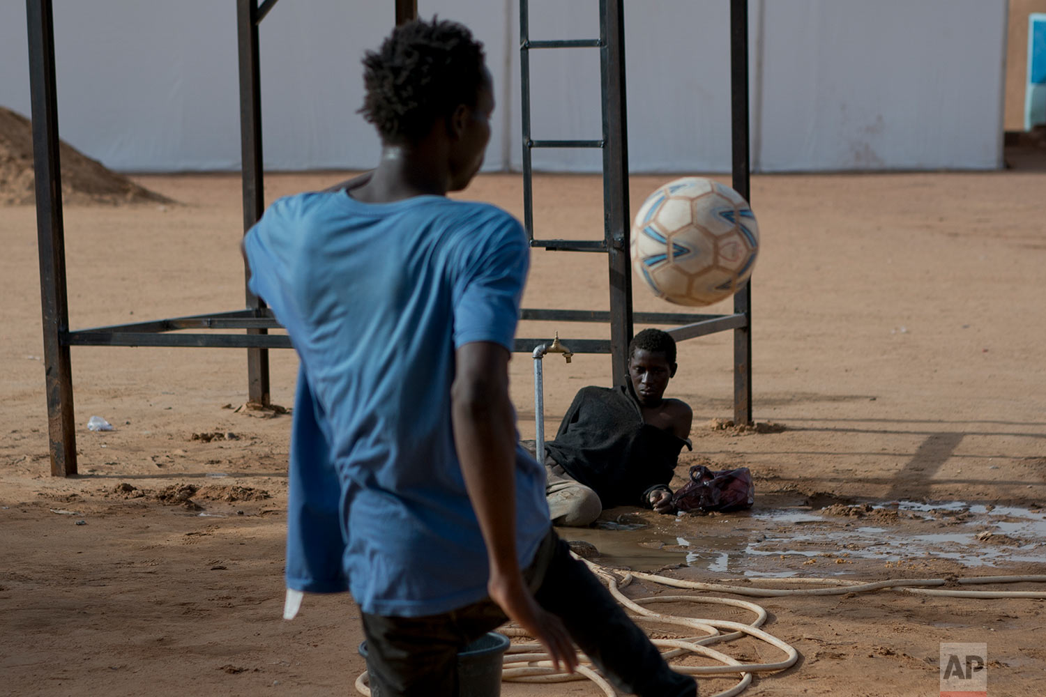  A young migrant who has been expelled from Algeria watches others play football in a transit center in Arlit, Niger, on June 1, 2018 (AP Photo/Jerome Delay) 