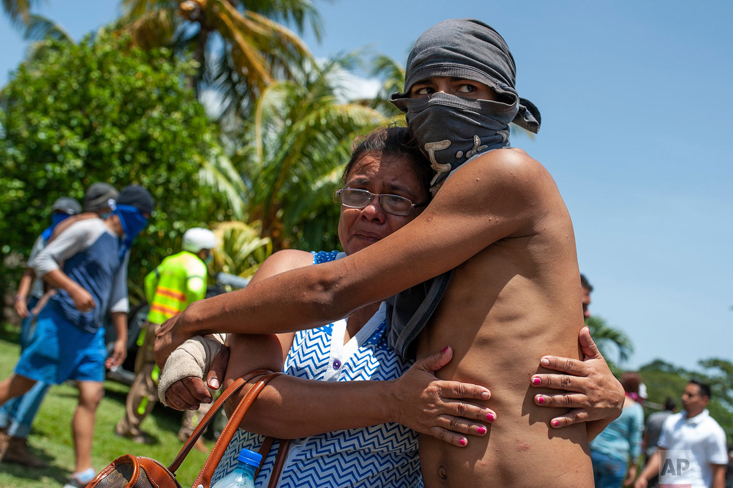  A masked, anti-government student who had taken refuge at Jesus of Divine Mercy church from an armed attack by police and government supporters is embraced by a relative after he was transported to the Cathedral with other students in Managua, Nicaragua, July 14, 2018. Cardinal Leopoldo Brenes negotiated with the president's office for the safe transfer of students out of the church and to the Metropolitan cathedral. (AP Photo/Cristobal Venegas) 