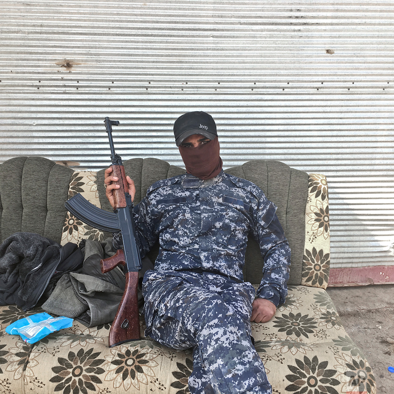 In this photo taken Thursday, Oct. 27, 2016,  Abdelyusef, no last name given, an Iraqi Federal Police officer, poses for a portrait at a checkpoint in the village of Al Hut, some 40 kilometers south of Mosul, Iraq. The push to kick the Islamic State out of Mosul has brought together an eclectic mix of Iraqis, young and old, police and soldiers, and a variety of irregular uniforms and equipment. (AP Photo/Marko Drobnjakovic)