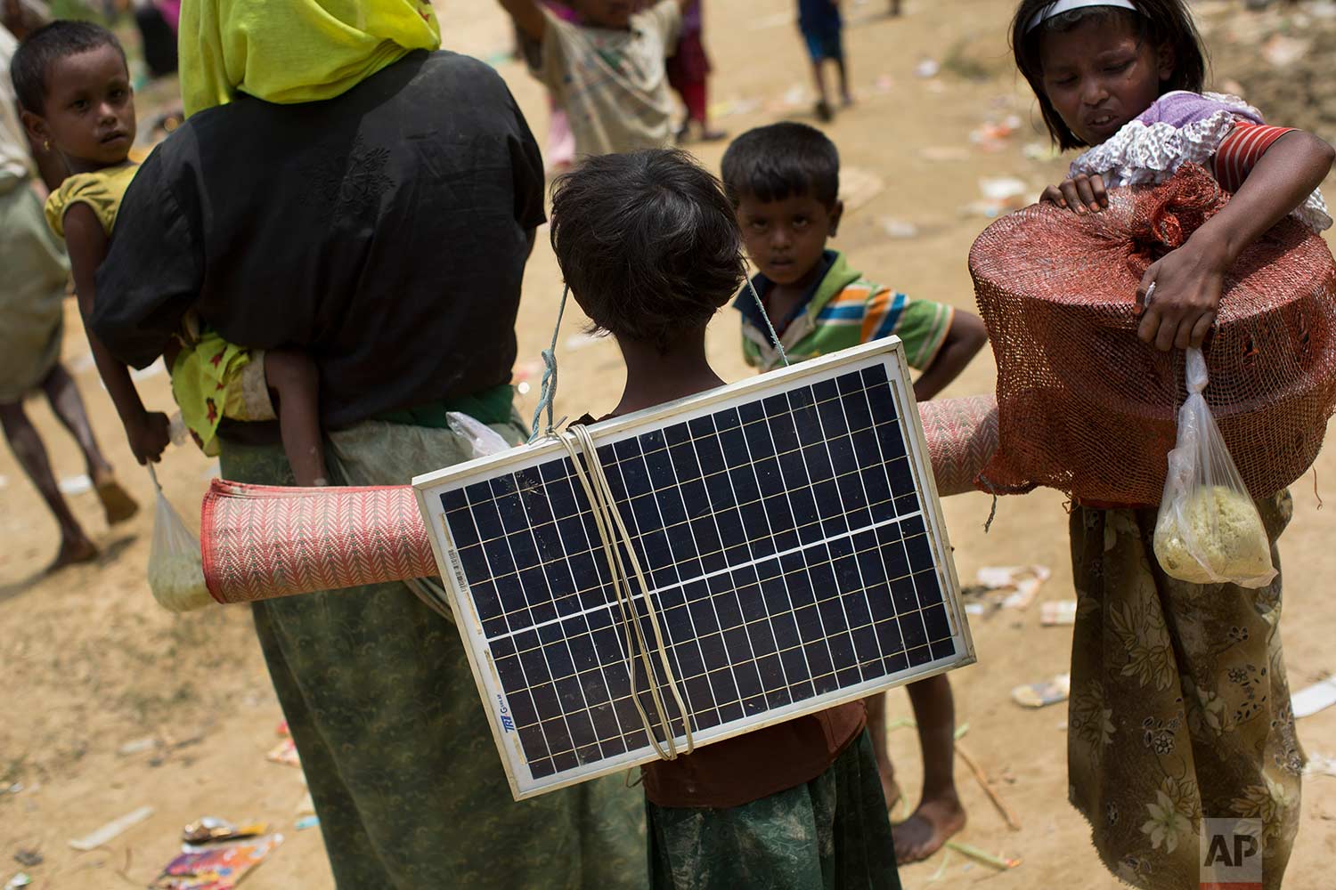 In this Thursday, Sept. 7, 2017, photo, a Rohingya Muslim child carries a solar panel as she crosses over the border from Myanmar into Bangladesh in Teknaf area. (AP Photo/Bernat Armangue)