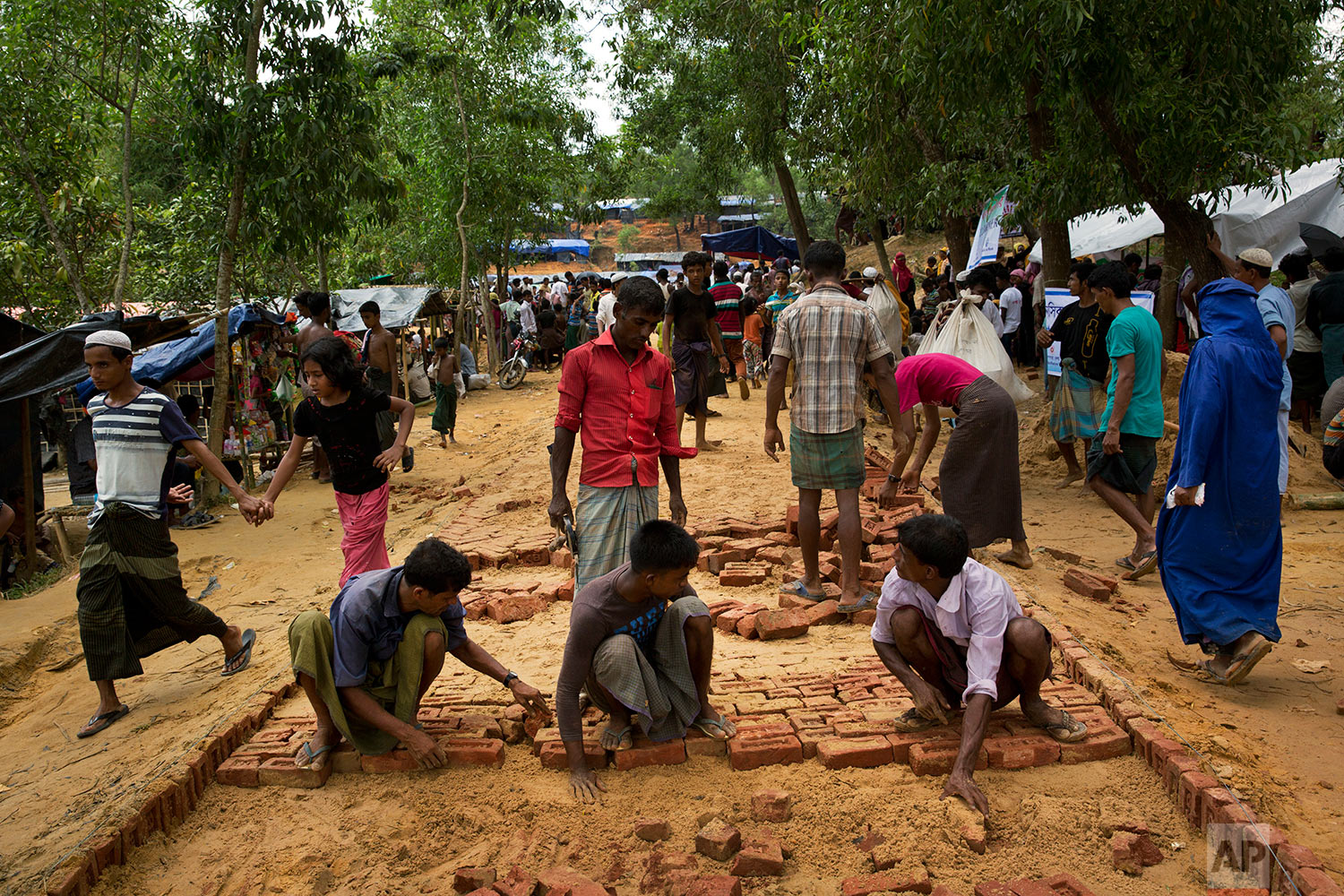 In this Saturday, Sept. 23, 2017 photo, people lay bricks to build a pavement at a new Rohingya settlement in Lambashia, near Kutupalong. (AP Photo/Bernat Armangue)