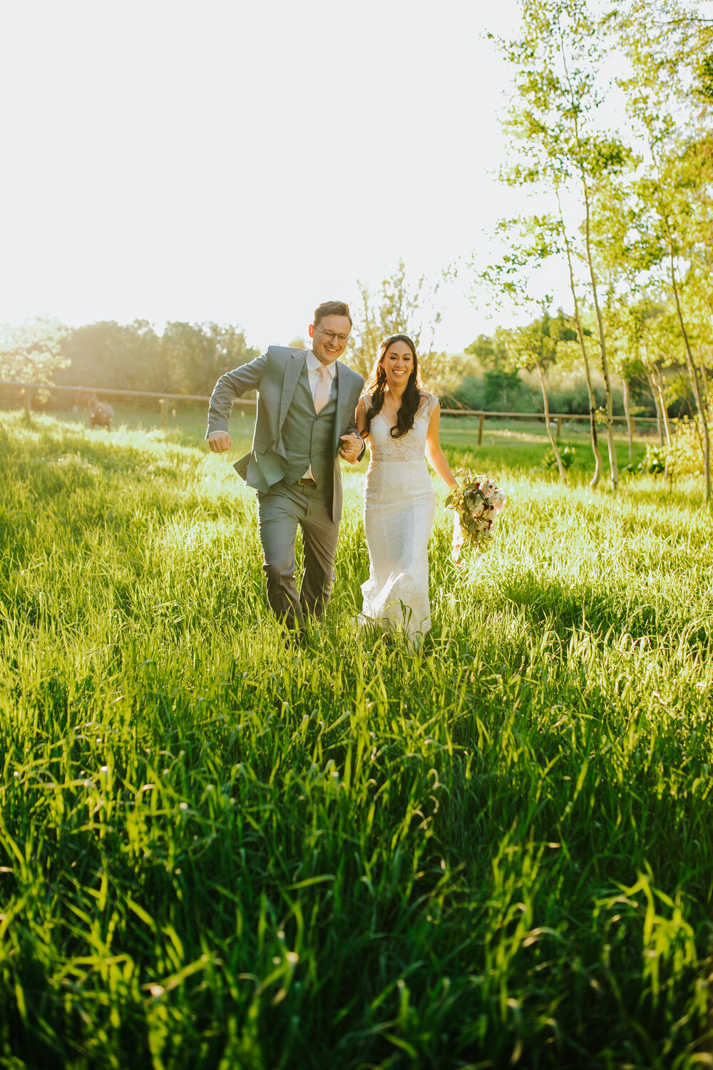 summer_wedding_outdoors_southern_traditions_joyful_knoxville_bride_couple_walking_grass_field_holding_hands_tennessee_photographer_look_for_the_light_photo_video