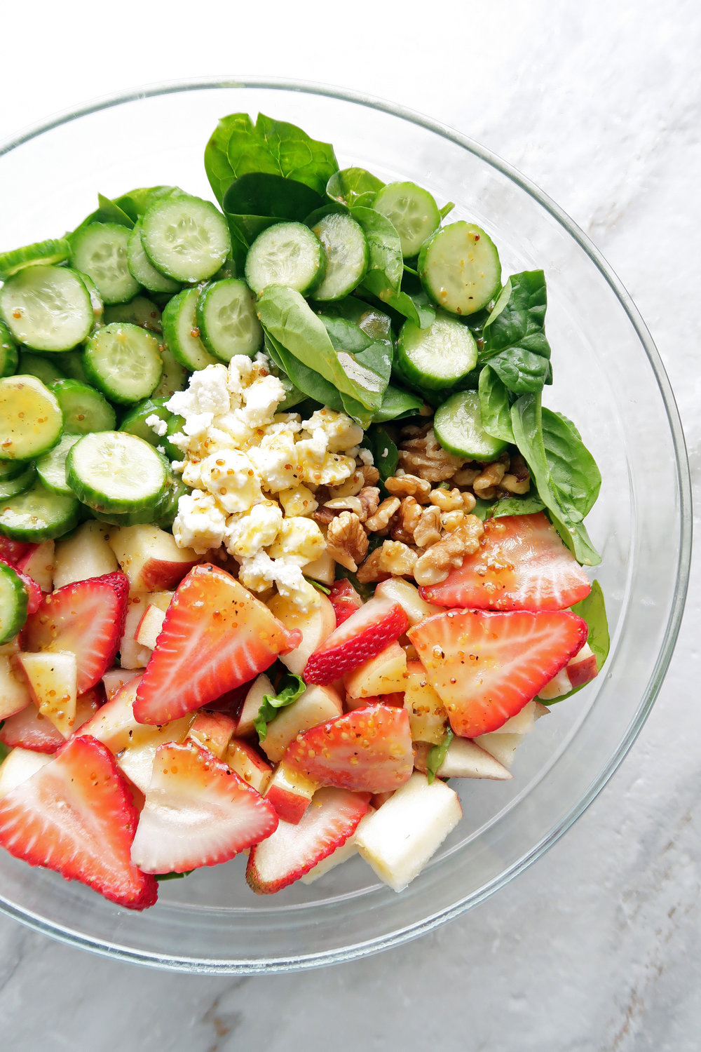 Fresh and healthy Strawberry Cucumber Spinach Salad with Apple Cider Vinaigrette in a large glass bowl.
