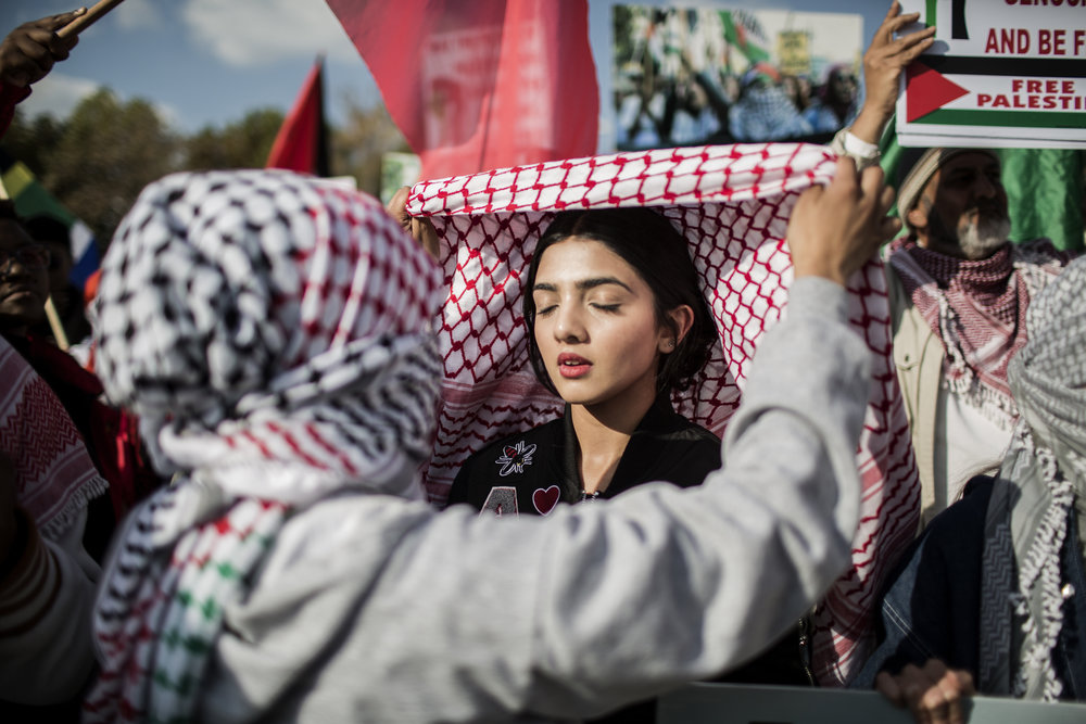  GULSHAN KHAN  gulshankhan.photoshelter.com  |  @gulshanii   A girl ties the Palestinian keffiyeh during a demonstration of members of pro-Palestinian groups and other civil society groups outside the U.S. Consulate General in Johannesburg, South Africa on Tuesday May 15, 2018 to protest against the killing of 59 Palestinians in clashes and protests the day before, coinciding with the United States formally moving its embassy in Israel from Tel Aviv to Jerusalem. 