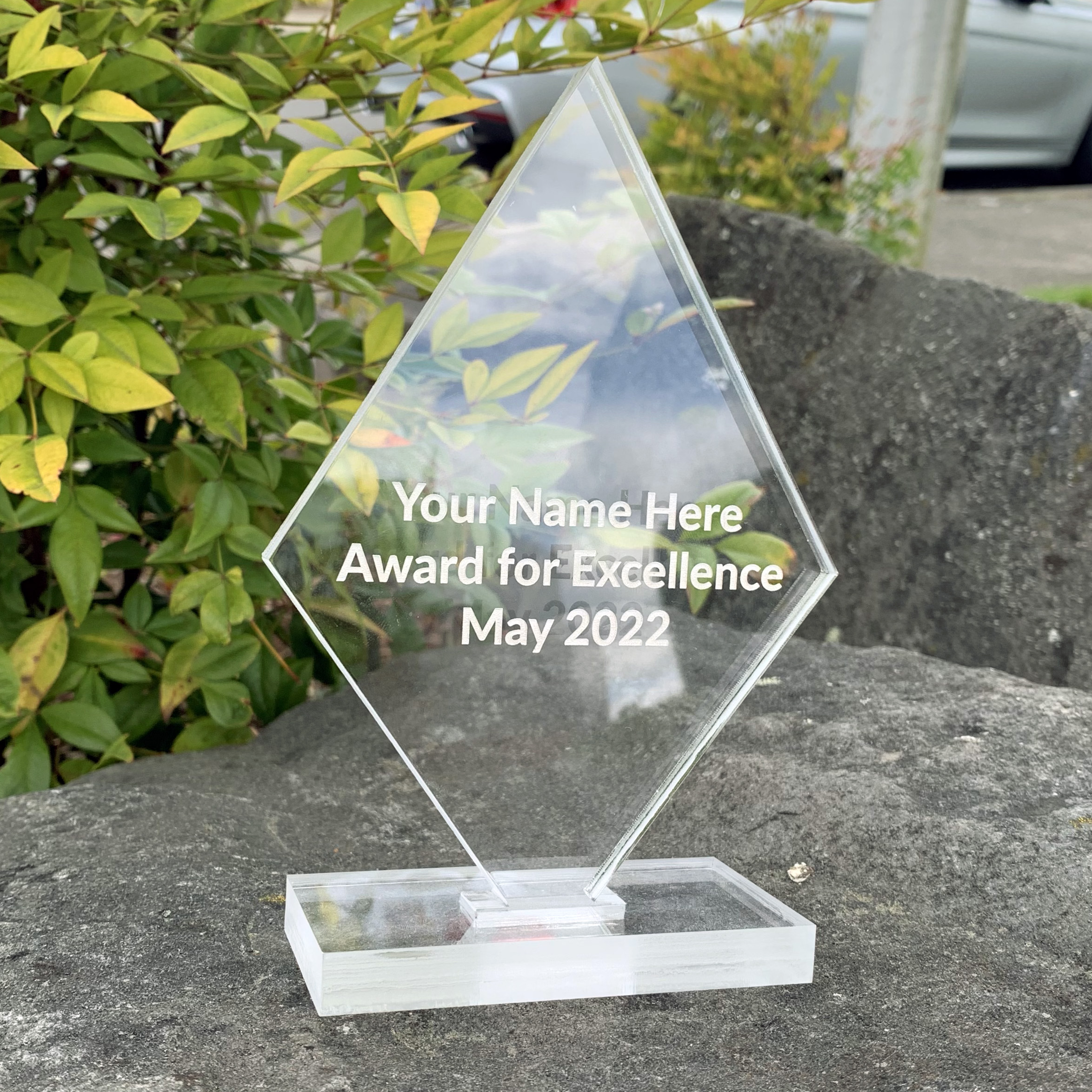 Laser Engraving: a diamond-shaped award made from clear acrylic with text engraved.