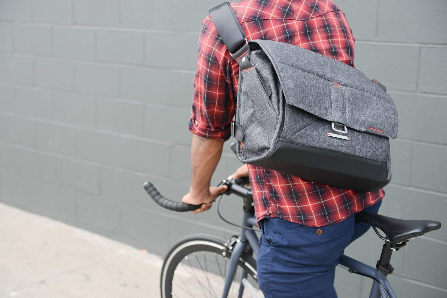 Photo of a man riding a bike with the 15" Everyday Messenger slung on his back.
