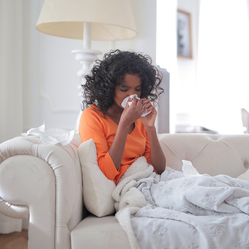 woman covered with blanket blowing nose hay fever