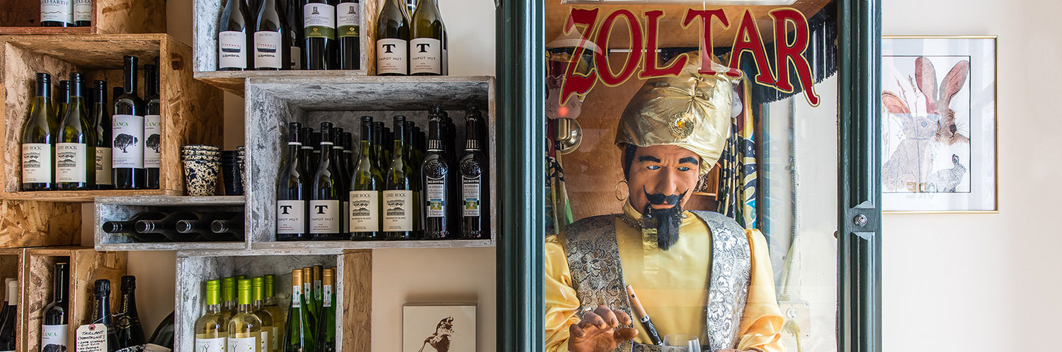 Shelves of wine next to a vintage Zoltar the fortune teller animatronic machine