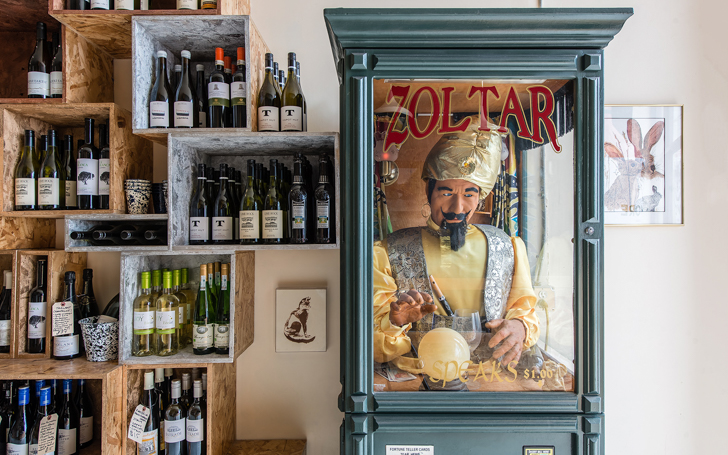 Shelves of wine next to Zoltar fortune telling machine