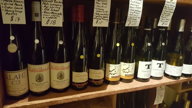 Closeup of wine bottles on shelves with handwritten tasting note cards