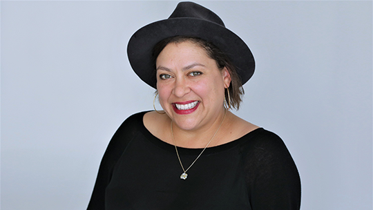 Portrait of Vinovore owner, Coly Den Haan wearing a black hat, black shirt and necklaces with red lipstick