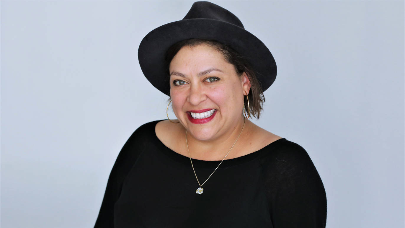Vinovore owner Coly Den Haan portrait wearing a black hat and blouse with a necklace
