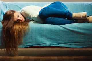Woman lying on her side on a couch clutching her stomach