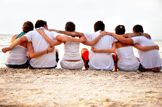 Back view of people hugging on a beach