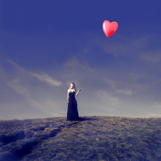 Woman in field holding heart-shaped balloon