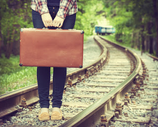 Girl on railway tracks with suitcase