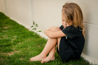 Little girl looking sad, sitting by herself