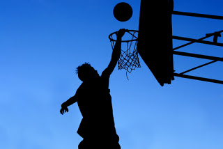 Man in silhouette shooting for basketball goal