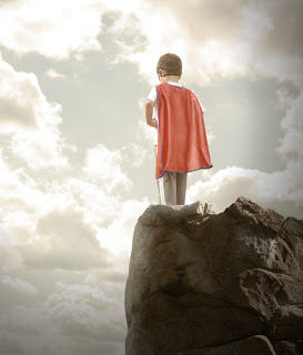 Little boy with cape standing on rock